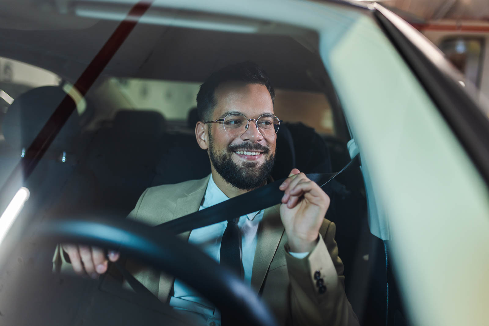 Young businessman putting a seatbelt on. Ready to drive off from